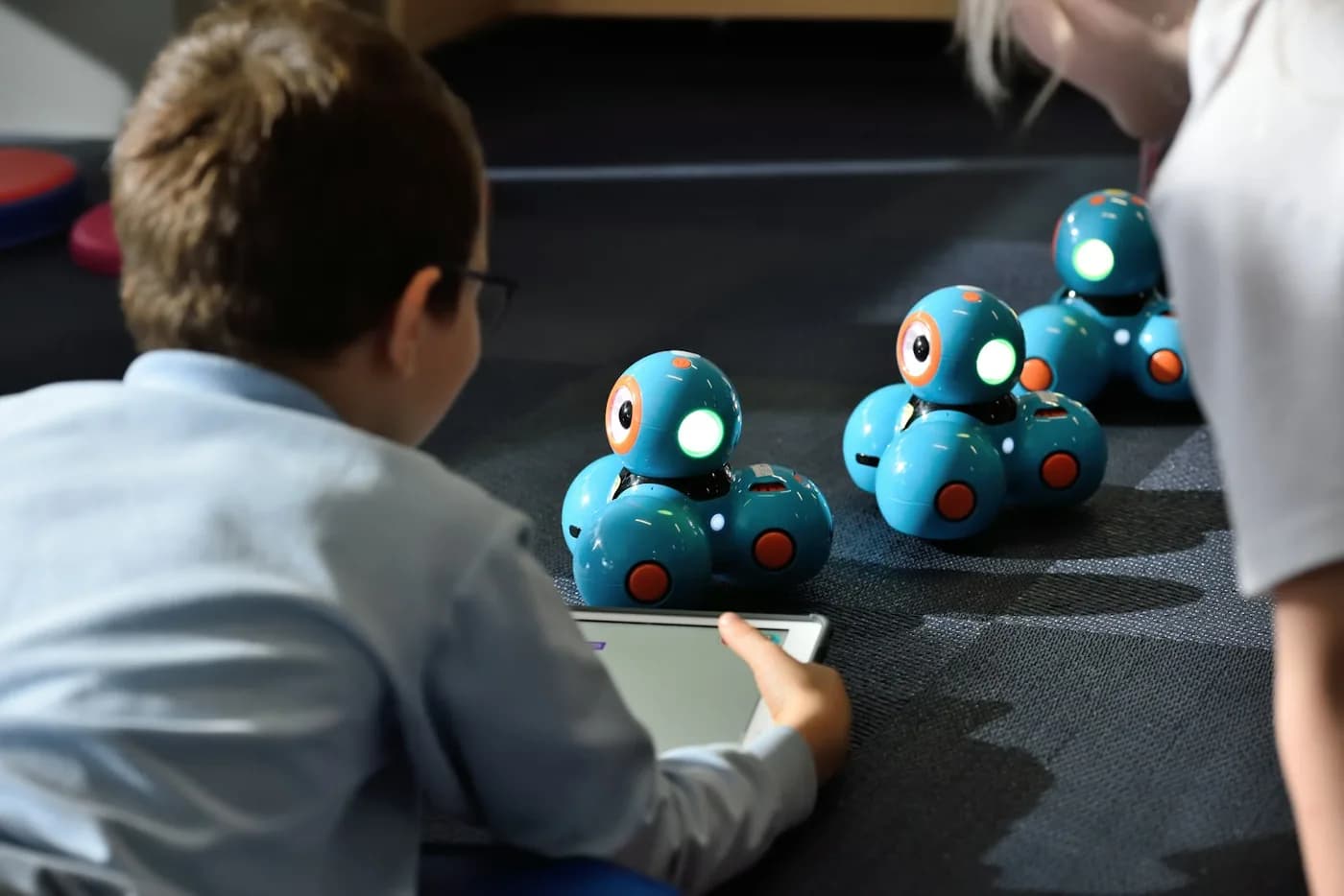 A boy programming a group of small robots from a tablet