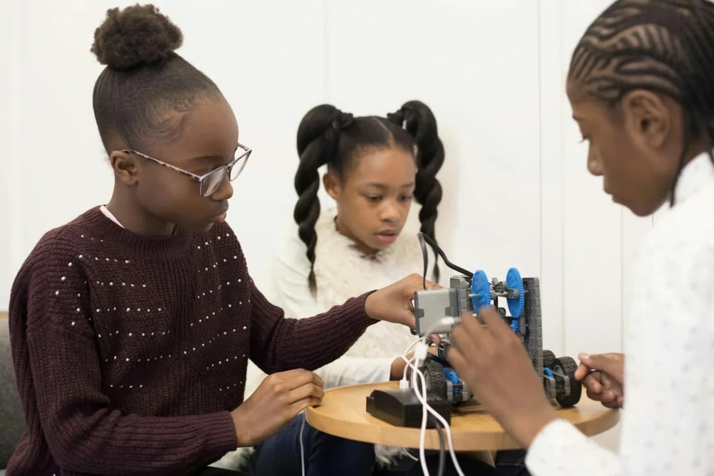 Three girls wiring up a robot they are building together